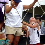 This little boy is on the road to being a tip-top sailor someday.  He watches as his action of pulling the main sail's rope causes it to rise up to catch the wind.