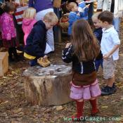 These children have fun playing '9 Men's Morris' colonial game on a tree stump.