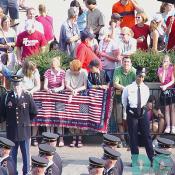 A family drapes a quilt over the baricades with the script "Indivisible, with Liberty and Justice for All".