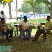 These three Haitian men sit in the shade of their tent and enjoy the sound of their self-made beats.