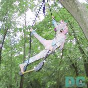 A colorful trapeze artist practices swinging through the trees before the party. 