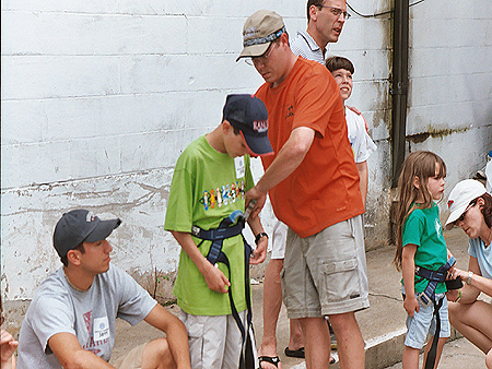 Owner and director of Outer Quest Outdoor Center, Dave Ridder helping a young climber gear-up for the climbing wall.