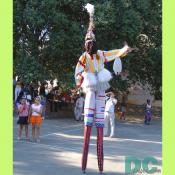 African performer on stilts wearing head dress.