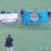 Young children holding up the flag of LA Galaxy and KOHLS.