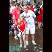 A father and daughter stand ankle deep in the rain water.