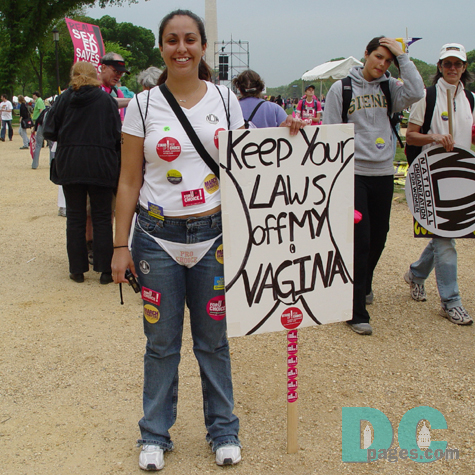 Pro-Choice activist demonstration stickers and PRO CHOICE underwear over her jeans. The activist holds up a demonstration sign - KEEP YOUR, LAWS, off MY, VAGINA [the words are between an abstract picture of naked woman] -