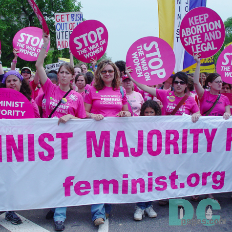 Wearing unifying pink shirts that read THIS IS WHAT A FEMIST LOOKS LIKE, The Femist Majority (feminst.org) marches down Constitution Avenue in Washington, DC.  They hold round pink signs: STOP THE WAR ON WOMEN and KEEP ABORTION SAFE AND LEGAL.