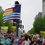 NARAL marchers hold signs stating ITS YOUR CHOICE ... NOT THEIRS while one marchers waves a flag with rainbow colors replacing the traditional red and white stripes.
