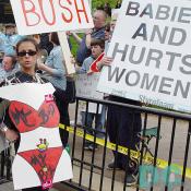 Pro-Choice activist wears a paper cutout - MY BOD IS MY BIZ.  Pro-Life advocates line the march route.