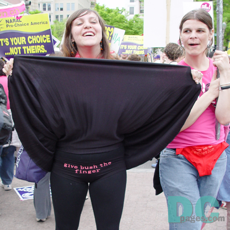 A marcher lifts her skirt to reveal shorts with a message: GIVE BUSH THE FINGER.