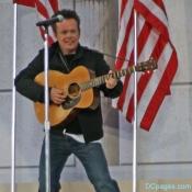 JOHN MELLENCAMP FLANKED BY AMERICAN FLAGS