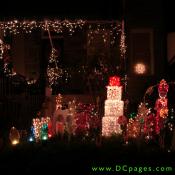 A boxed snow man, toy soldier, candy canes, large multi colored lightbulbs, and white string lights can be seen on this display.