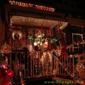 A candy cane reindeer crossing, red bows, santa claus, a Christmas star, a wreath, and many yards of multicolored stringed lights are on display at this home.