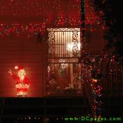 A lit Santa Claus waves on a porch covered in Christmas Lights.