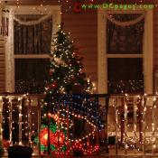 A smiling snowman display, a lit Christmas tree, and strands of white lights can be seen at this home.