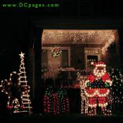 A lit ginger bread man holding a candy cane, Santa Claus, a reindeer, a green and red present, wreath, and lights fill this yard with good cheer.