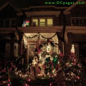 A multcolored train, red and green bows, and other outdoor holiday decorations light up the front of this home.