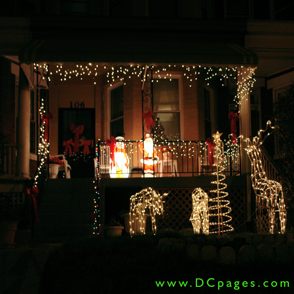 A brightly lit Frosty and Santa stand on the front porch filled with red ribbons and cascading white light. Three mechanized reindeer move around a bright spiral Christmas tree on the front yard.