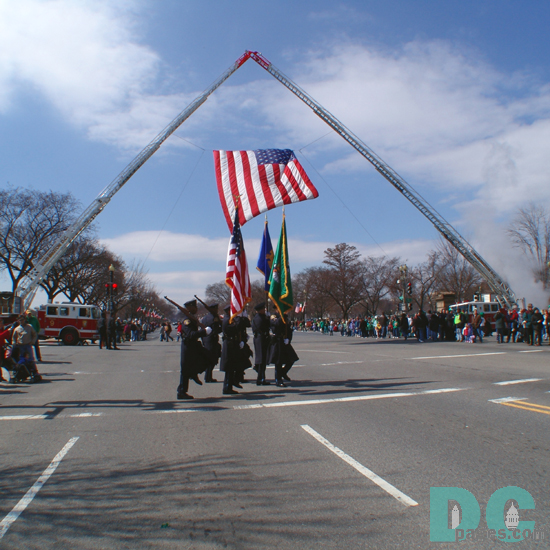 DC Color Guard march under an American flag hung from two giant fire truck ladders.