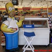 Homer Simpson enjoys a couple of hot dogs inside the Bladensburg Kwik-E-Mart.
