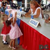 These two girls show off their pink ribbons to one of the baby beauty contest judges. 