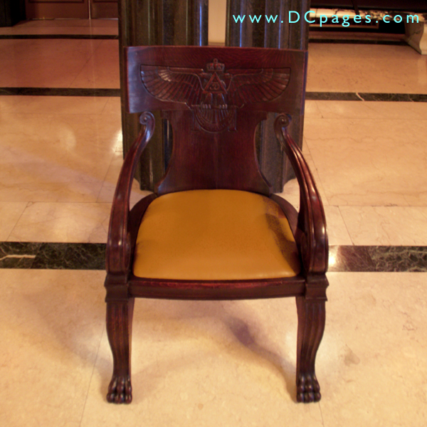 This wood chair is modeled after a High Priests seat in the theater of Dionysius. There is a carved eagle with Egyptian styled wings simular to ones seen throughout the building.