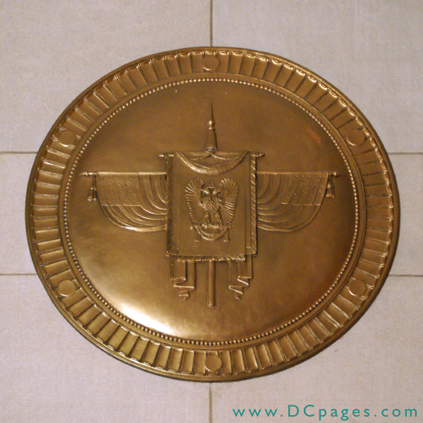 Bronze plaque is banner of the Supreme Council with American flags on both sides. The double-headed eagle is the unique symbol of the Scottish Rite, and the motto of the Thirty-third Degree is Deus meumque jus (God and my right).