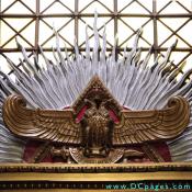 Bronze sculpted double-headed eagle spreads its wings in front of a red pyrimid.