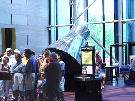 Onlookers pass the Mercury Space capsule in the front lobby.