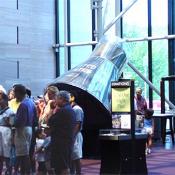 Onlookers pass the Mercury Space capsule in the front lobby.