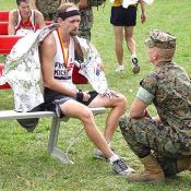 A Marine helps an exhausted man try to catch his breath after the race.