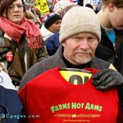 Man holds up shirt - FARMS NOT ARMS