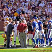 Sam Huff, Redskins, Giants, game officials observe the toss.  A network camera allows fans from Washington, New York, and the rest of the world to watch on their television screens.