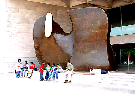 A group of students take a break in front of Henry Moore's bronze work Knife Edge Mirror Two Pieces