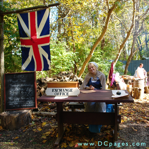 A smiling colonial woman welcomes guests to the Market Fair. There is a British 'Union Jack' flag hangs on the left representing the time when this area was under English rule.