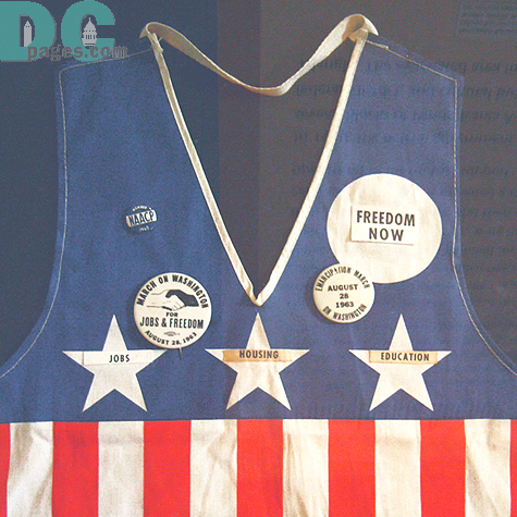 Veast worn at the March on Washington, 1963:
On August 28, 1963 more than 200,000 demonstrators convented in D.C. for the March on Washington for Jobs and Freedo. Civil rights, labor, and religious organizations collaborated and compromised to produce an event notable for its unified messages and coordinated appearance. 
Both aspects are apparent in this vest, worn by a March on Washington demonstrator. The red, white, and blue of the vest matched the official signs held by the participants to symbolize their patriotism. The buttons and tags attached to the vest point to the main themes of the protest- jobs, education, and equal rights. The clasped hands symbol decorated the most popular button. The sale of hundreds of thousands of these buttons helped raised money for the event.  Collection of Jerome Gray