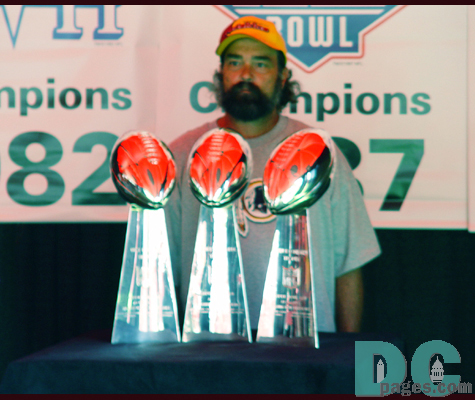 A fan poses with the three Super Bowl trophies won by Coach Gibbs during his first tenure with the Redskins.