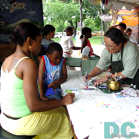 A tribe member helps this mother and son to use the stencils properly in the Arts and Crafts tent.