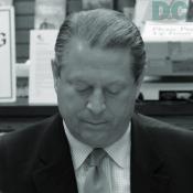 Al Gore looks down to sign his book.
