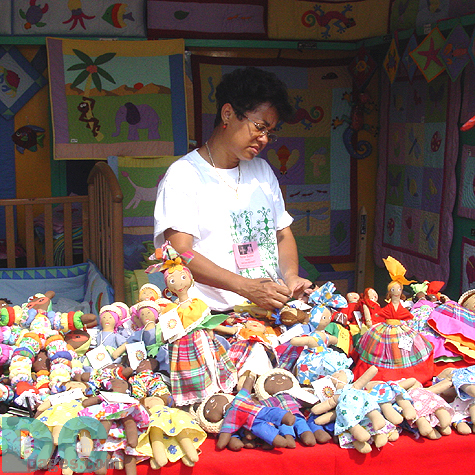 A woman sells handmade dolls, quilts and other baby products at her stand in the Haitian art stands.
